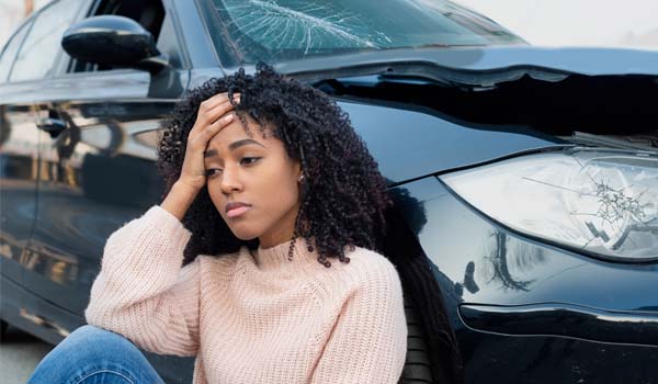 Woman Sitting Next to Car After an Accident